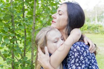 Embracing mother and daughter in summer on green background