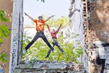 Father and son are jumping through ruins in summer day