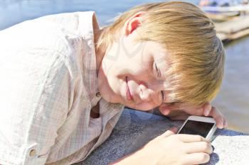Blonde smiling boy with cellular phone in sunlight