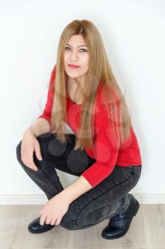 Vertical photo of girl is squatting with long brown healthy straight hair