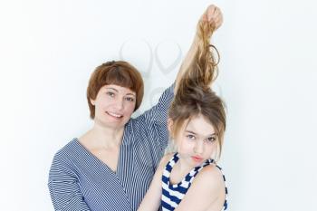 Mother and daughter playing with blond long hair near white wall