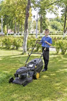 Cute smiling boy are working with lawn mower in summer