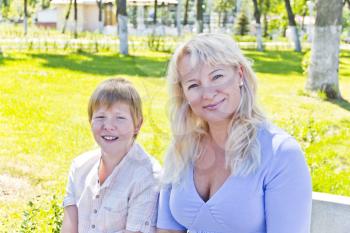 Happy blond woman and son smiling in the summer park