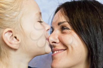 Cute smiling daughter kissing her mother to nose