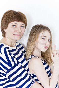 Happiest mother and daughter near white wall in striped clothes