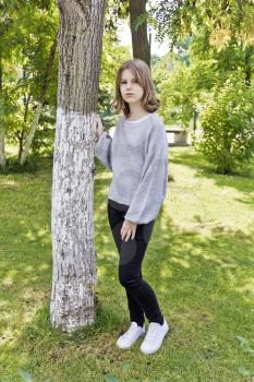 Beautiful girl fourteen years old lean on the tree