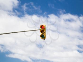 Red traffic light on cloud sky background. Photo.