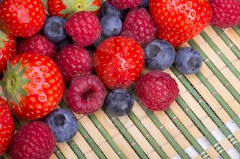 Variety of berries - trawberries, blueberries, raspberries scattered on a table, top view