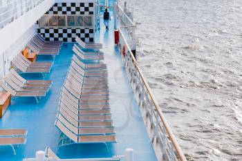 sunbath chairs on side of cruise liner at autumn morning