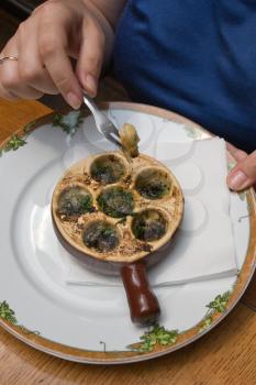 plate with baked snail, piece of bread with a fork, diped it in the oil