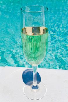 glass of white wine on pool board outdoor
