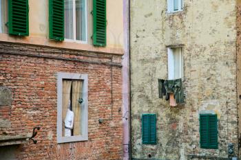 wall with windows and sculpture in old town (Siena, Italy)