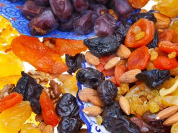 many dried sweet fruits and nuts on plate close up
