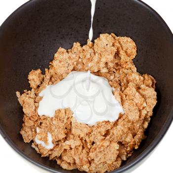 top view of yoghurt is poured into bowl of cereal