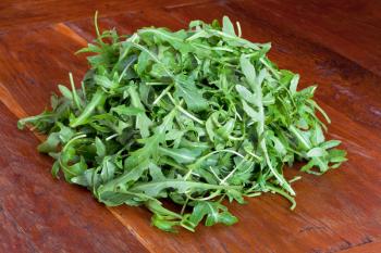 heap of fresh rucola salad on wooden table