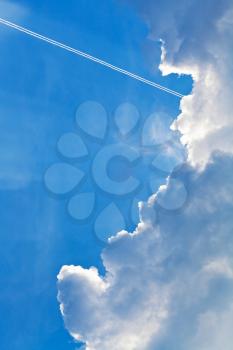 cloudscape with trace of air plane in blue sky in summer evening
