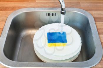 washing-up by dish sponge in metal washbasin in kitchen