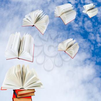 open books fly out of pile of books with cloudy blue sky background