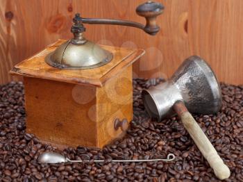 retro manual coffee mill , copper pot, spoon on many roasted coffee beans