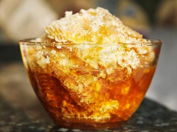 fresh honey in comb in glass bowl at stone table