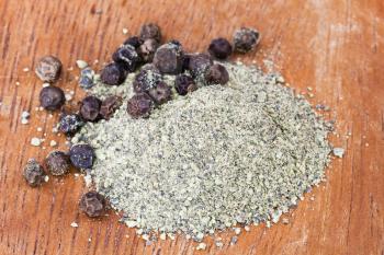 freshly ground black pepper and peppercorns on wooden board