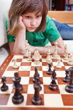 little girl playing chess game lying on couch