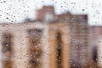 rain drops on glass with brick urban houses background