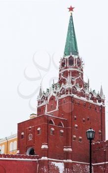 snow in Moscow - red Troitskaya Tower of Kremlin in winter snowing day