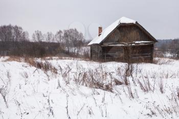 abandoned rural house in snow-covered village in winter day