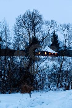 old snowed wooden house in village in blue winter evening