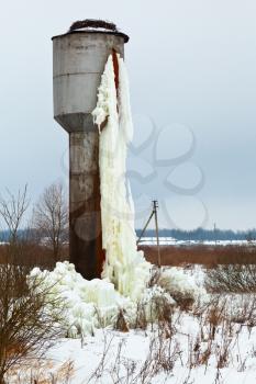 frozen water tower in country field in winter day