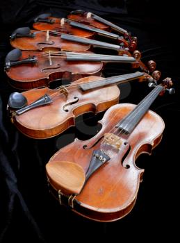 different sized violins on black velvet close up