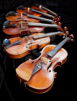 different sized violins with black background close up