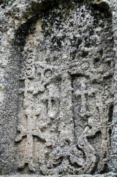 carved cross on ancient stone wall of medieval geghard monastery in Armenia