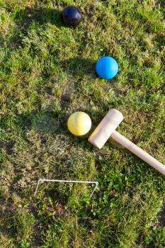top view of balls and mallet for game of croquet on green lawn in summer day