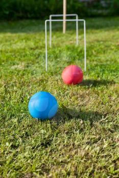 blue and red balls in game of croquet on green lawn in summer day