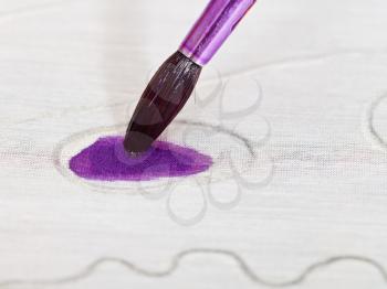 drawing violet ornament on silk canvas with brush close up