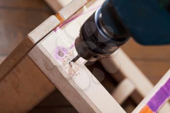 assembling of wooden chair with drill close up