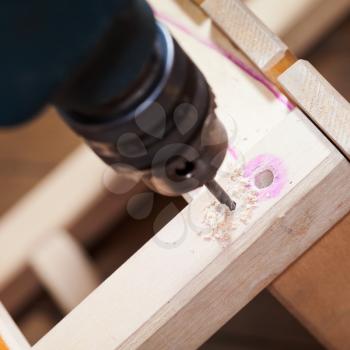 assembling of wooden stool with drill close up