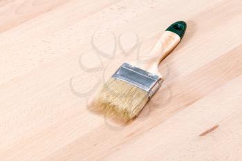 new paint brush on beech wooden furniture board