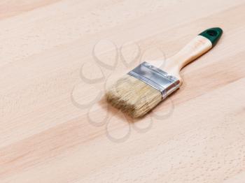 new paint brush on surface of beech wooden table top