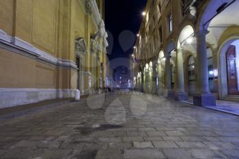 arcade and facade of st peter cathedral on via Altabella in Bologna, Italy at night