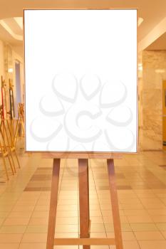 big picture frame with white cut out canvas on easel with yellow light gallery background