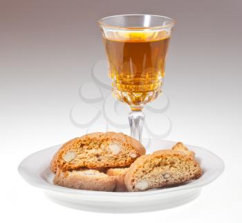 crystal wine glass with sweet white wine and italian almond cantuccini on saucer