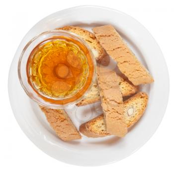 top view of crystal glass with sweet white wine and italian almond cantuccini on saucer isolated on white background