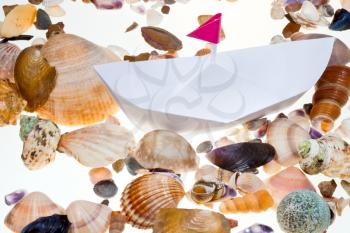 hand made paper boat on background from sea shells