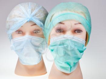 two women's dummy doctor heads wearing textile surgical cap and medical protective mask