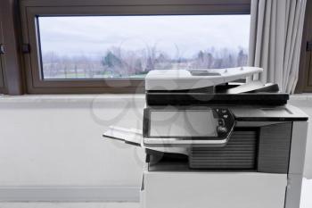 big grey copier in grey office and color life beyond window