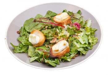 green salad with goat cheese and croutons on plate isolated on white background