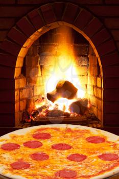 italian pizza with sausage and open fire in wood burning oven